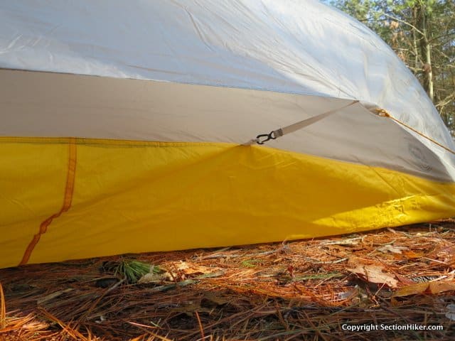 The rain fly clips to the the inner tent at its midpoint using mitten hooks, whch help pull out the tent sides to create more interior volume. This is why a minimum of 8 stakes are required to pitch the tent and more in windy conditions. 