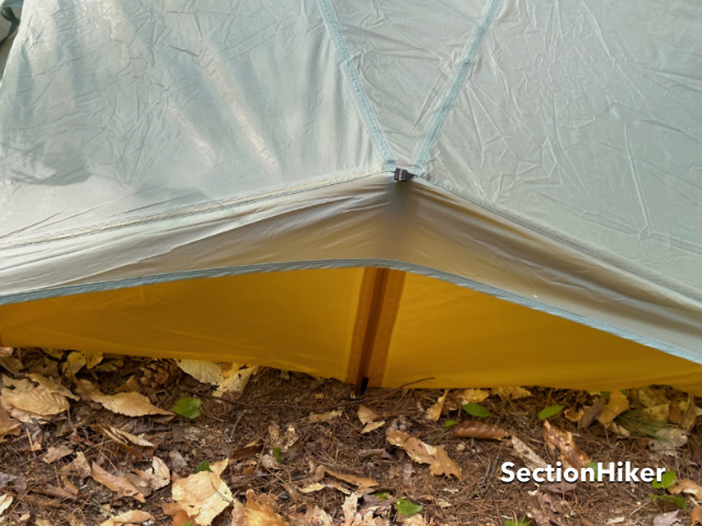 The gold poles slot into a sleeve and grommet at the head and foot ends of the tent.